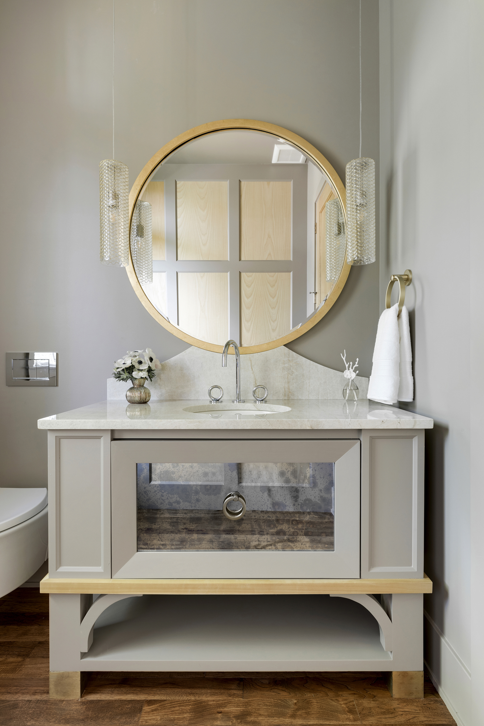 A neatly decorated vanity bathroom sink with circle mirror